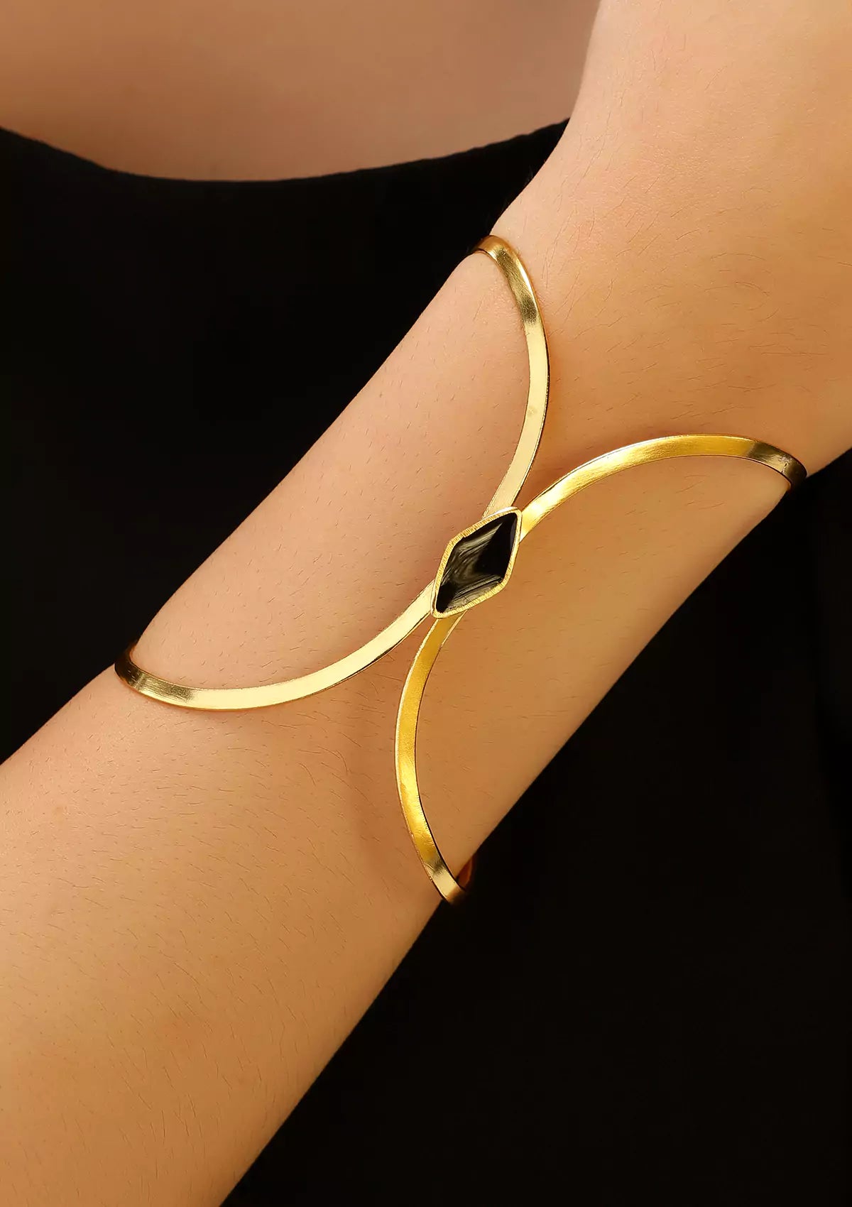 Gold bracelet on a person's wrist with a black background